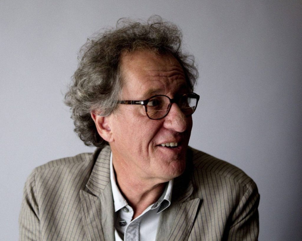 Geoffrey Rush portrait in pinstriped blazer glasses soft lighting minimalist studio background Wallpaper