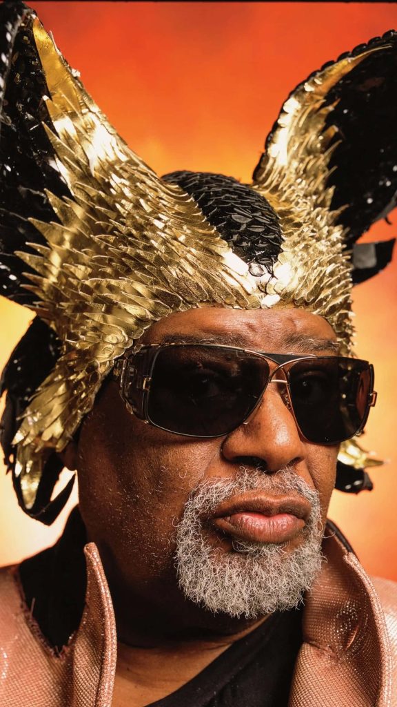 Close-up of George Clinton in gold black spiked headpiece and sunglasses vibrant funk portrait Wallpaper