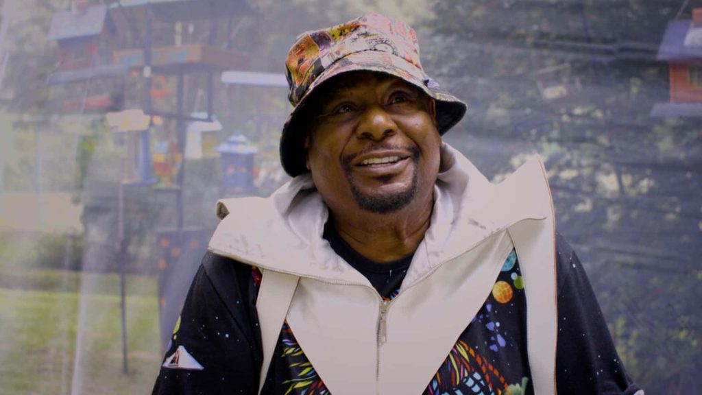 George Clinton funk legend wearing colorful bucket hat and space shirt with warm smile wallpaper