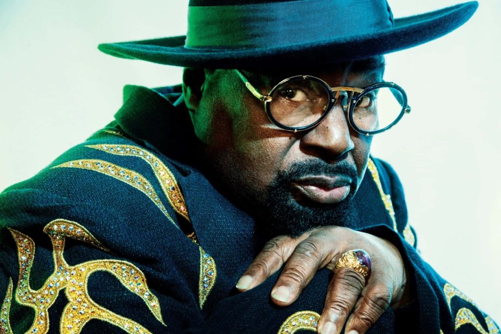George Clinton portrait with round glasses dark hat and gold embroidered sequin jacket wallpaper