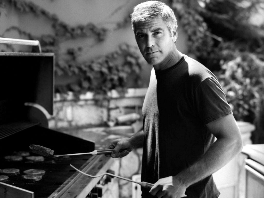 George Clooney grilling pork barbecue outdoors with classic barbecue setup background wallpaper