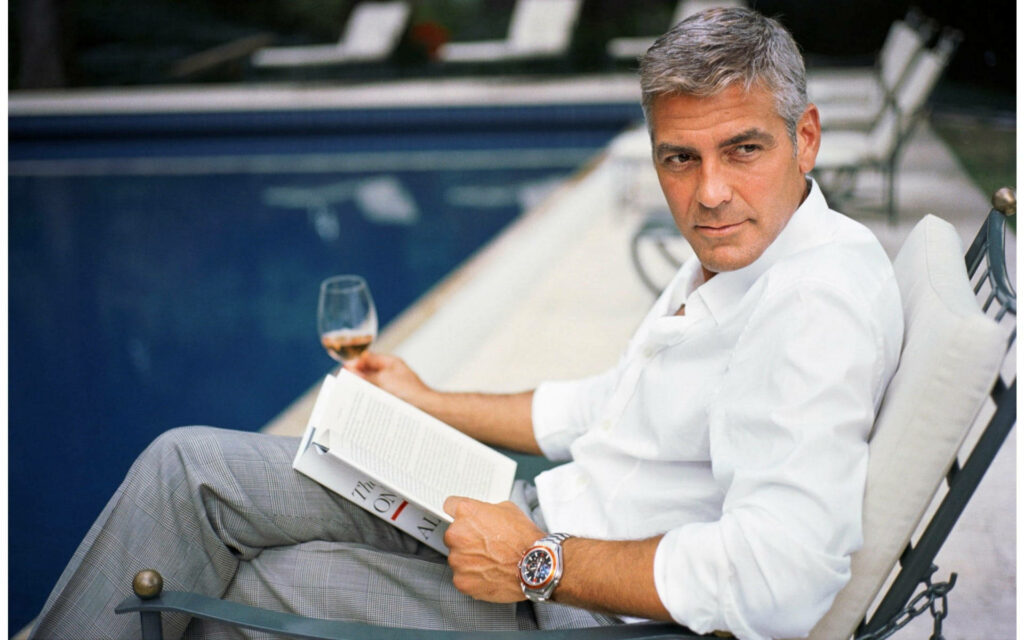 George Clooney relaxing poolside with book and wine exuding sophistication American producer Wallpaper