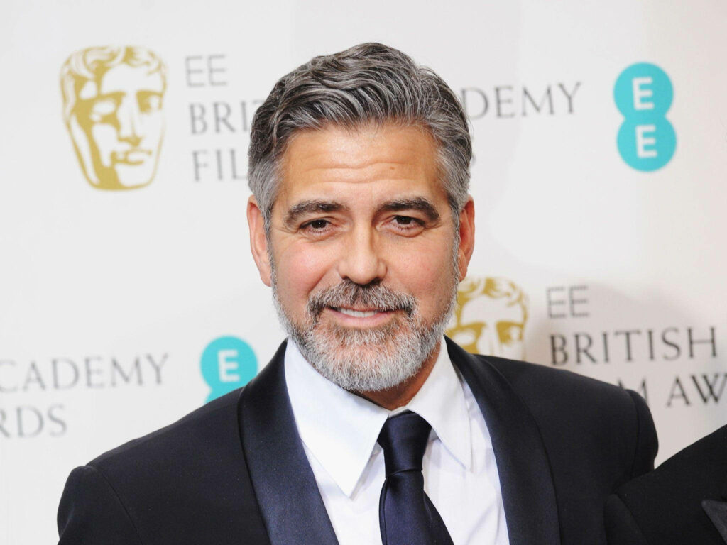 George Clooney in sharp suit posing confidently on red carpet at EE British Academy Film Awards Wallpaper