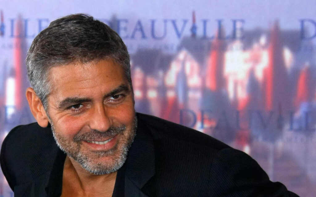 George Clooney smiling in soft focus wallpaper highlighting his charismatic timeless style