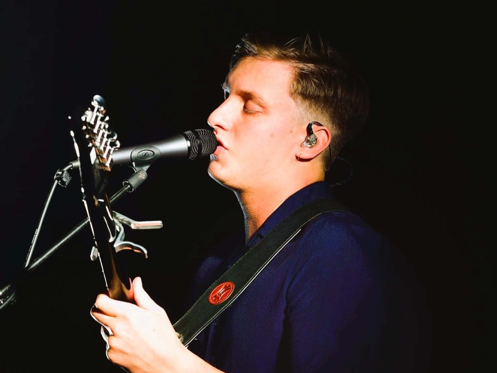 George Ezra live concert wallpaper soulful profile singing acoustic guitar dark background