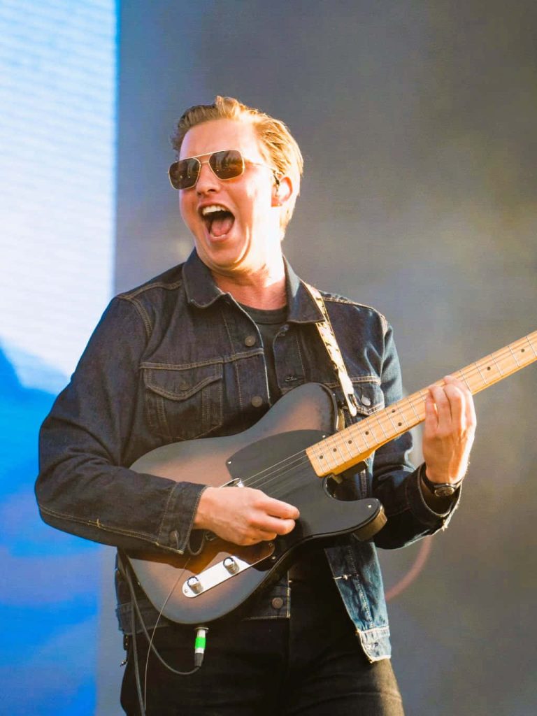 George Ezra live concert vibrant wallpaper singing playing electric guitar bright stage lights