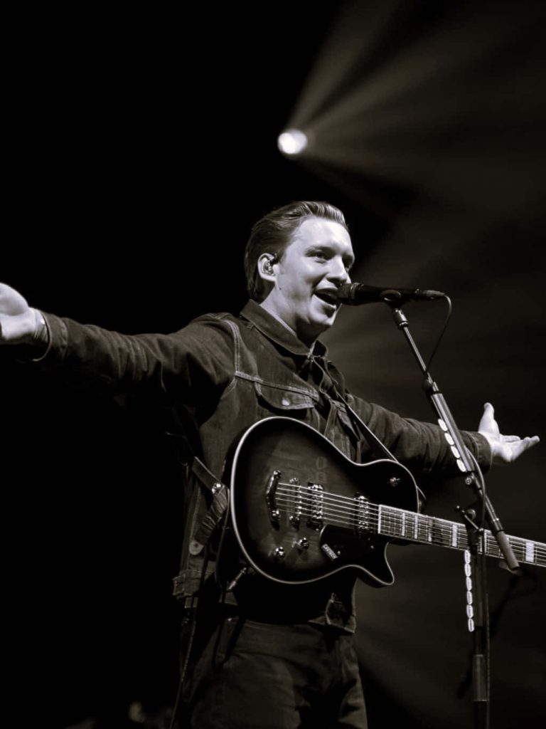 George Ezra mid-song with electric guitar under spotlight black and white concert wallpaper