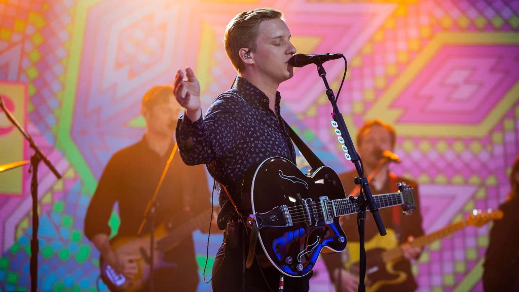 George Ezra live performance with black Gretsch guitar vibrant pink yellow geometric backdrop wallpaper