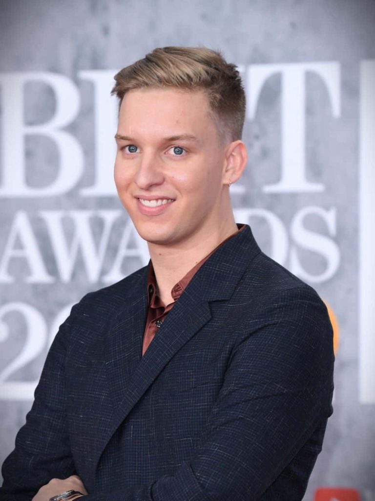 George Ezra smiling in dark blazer and brown shirt at BRIT Awards professional portrait wallpaper
