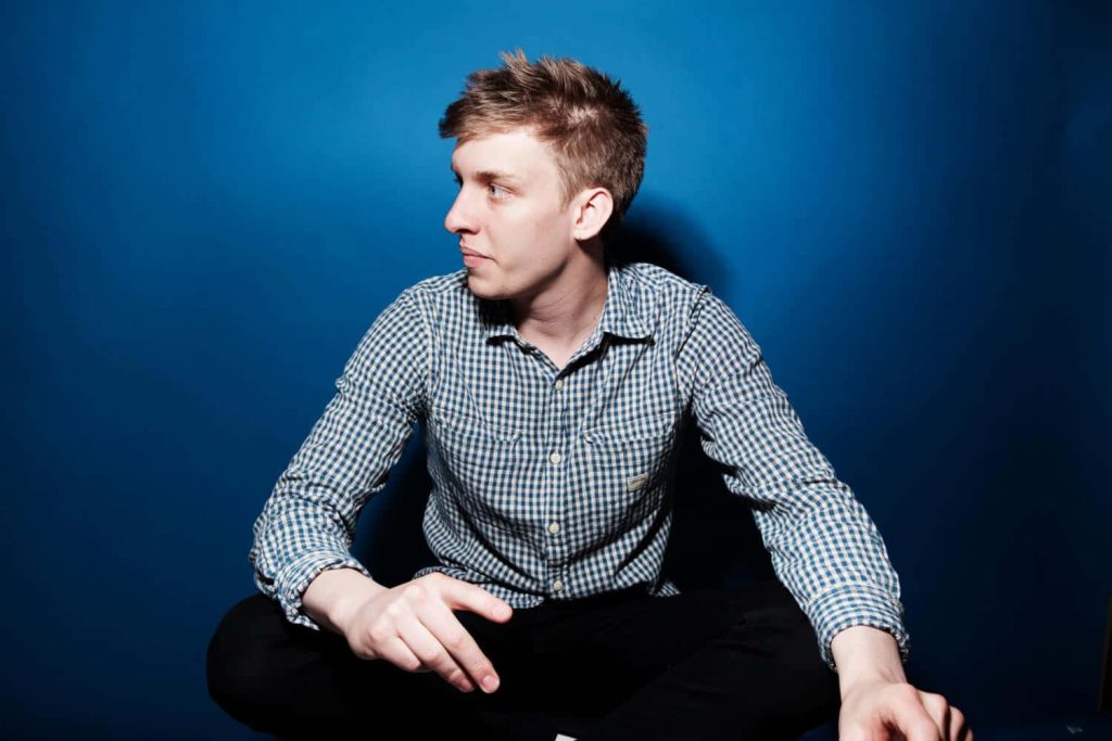George Ezra in blue white checkered shirt against vibrant blue wall minimalist portrait wallpaper