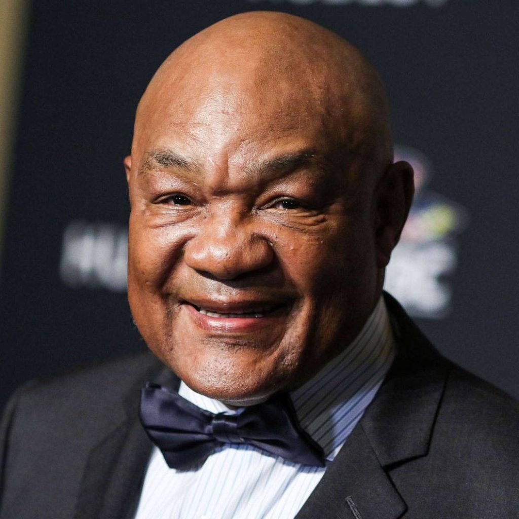 George Foreman portrait wallpaper smiling in suit striped shirt bow tie dark background