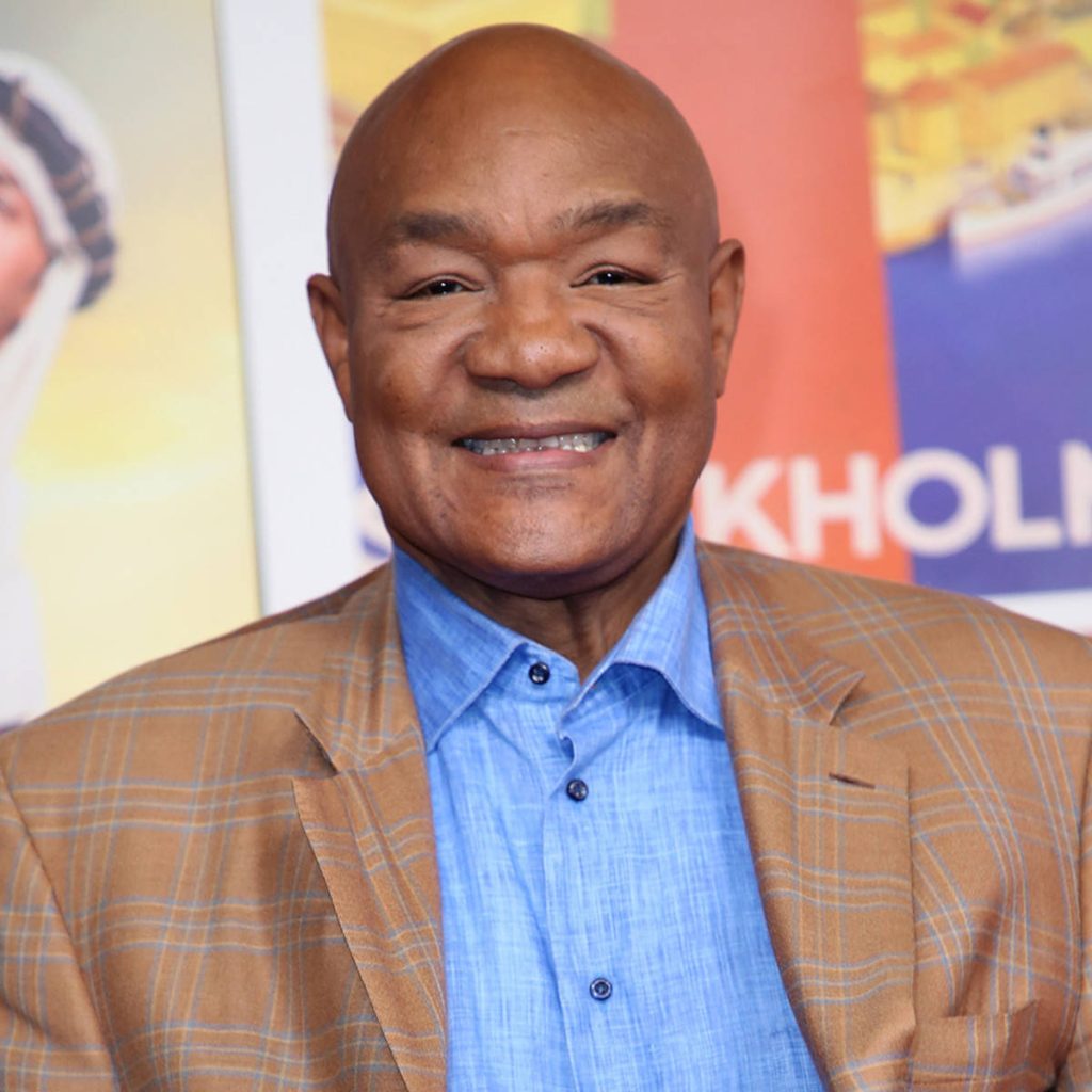 George Foreman smiling in brown plaid blazer and blue shirt professional portrait wallpaper