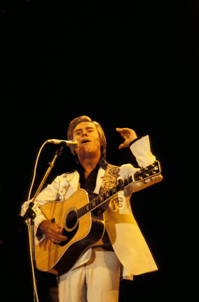 George Jones vintage live performance singing acoustic guitar white suit spotlight wallpaper