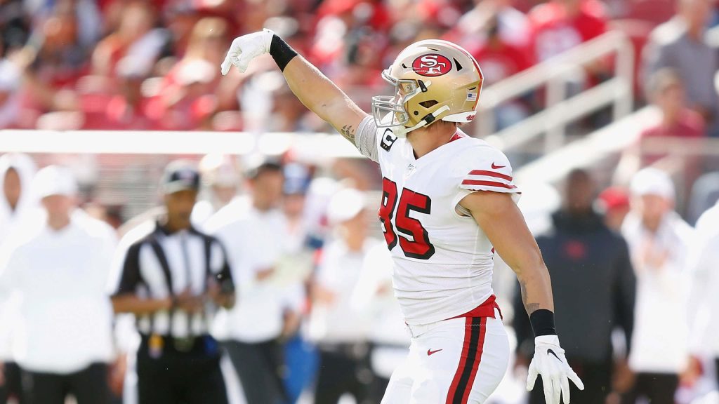 NFL star George Kittle in white 85 jersey and gold helmet raising arm on field wallpaper