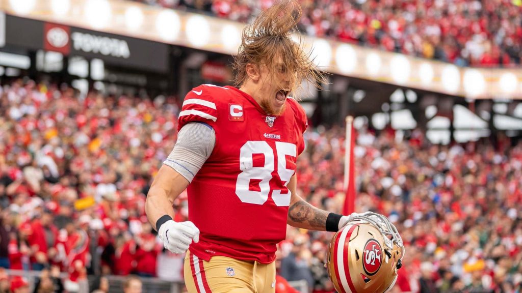 George Kittle in red 85 jersey celebrates on field with roaring crowd 49ers NFL wallpaper