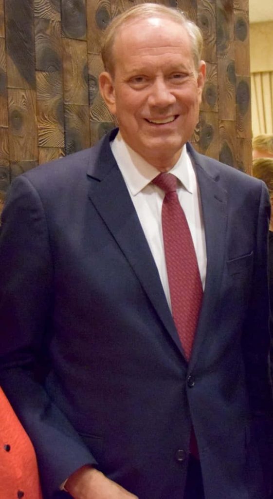 Formal portrait of George Pataki in navy suit and maroon tie with dark wood background Wallpaper
