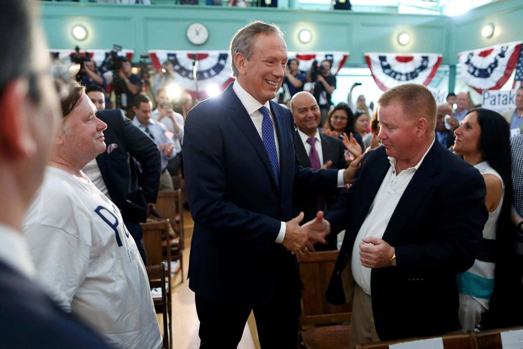 George Pataki shaking hands at a lively campaign event with patriotic decor and supporters Wallpaper