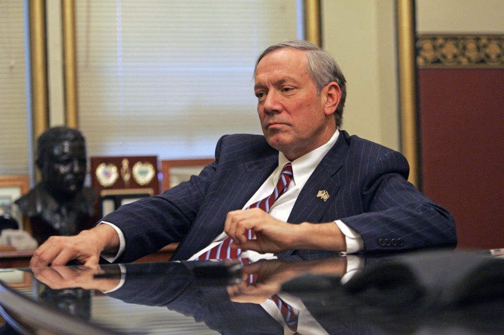 Former New York Governor George Pataki in pinstripe suit seated in office with serious expression Wallpaper