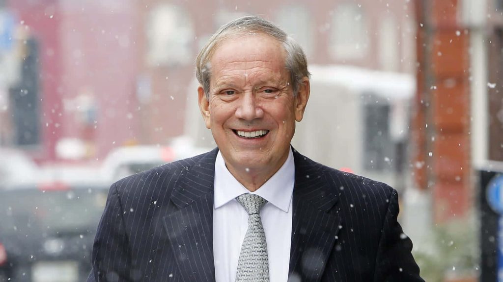 Former Governor George Pataki smiling in pinstripe suit during gentle snowfall urban winter scene Wallpaper