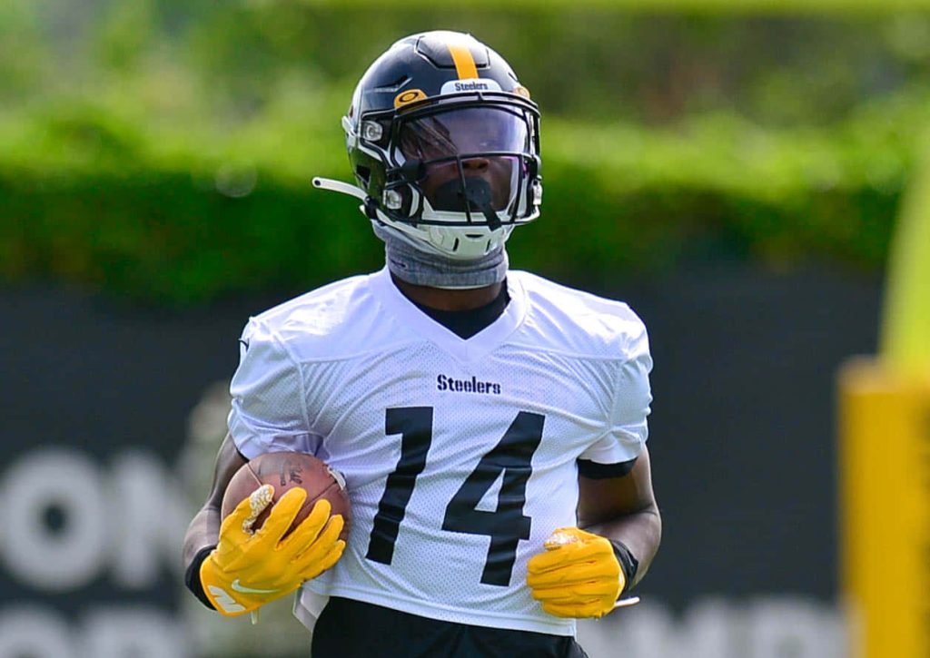 Pittsburgh Steelers WR George Pickens in white jersey 14 holding football during intense training camp Wallpaper