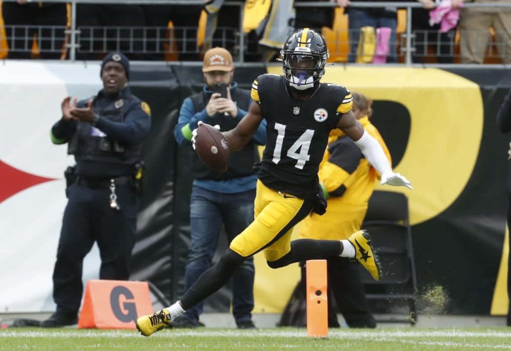 NFL star George Pickens in black and gold Steelers uniform #14 running on field wallpaper