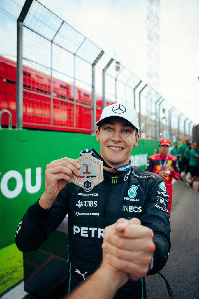 George Russell smiling in Mercedes AMG gear holding first place F1 Sprint medal vibrant wallpaper