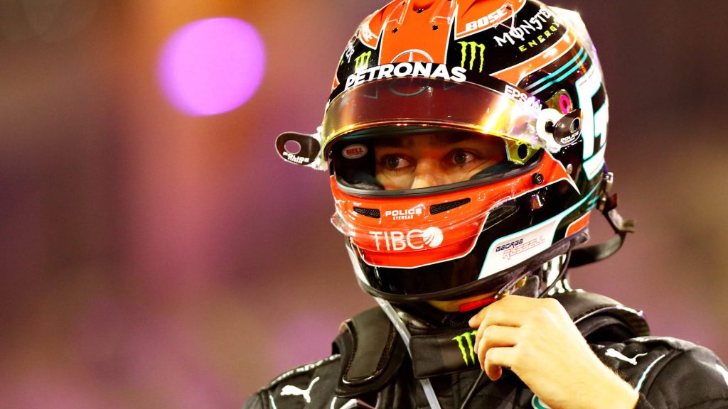 Close-up of F1 driver George Russell in branded helmet with vibrant pink purple bokeh background Wallpaper