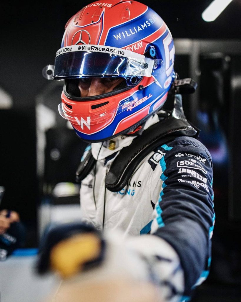 F1 driver George Russell in Williams Racing suit and helmet with arm extended wallpaper