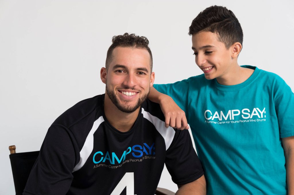MLB star George Springer smiling with camper in Camp SAY shirts promoting stuttering support Wallpaper
