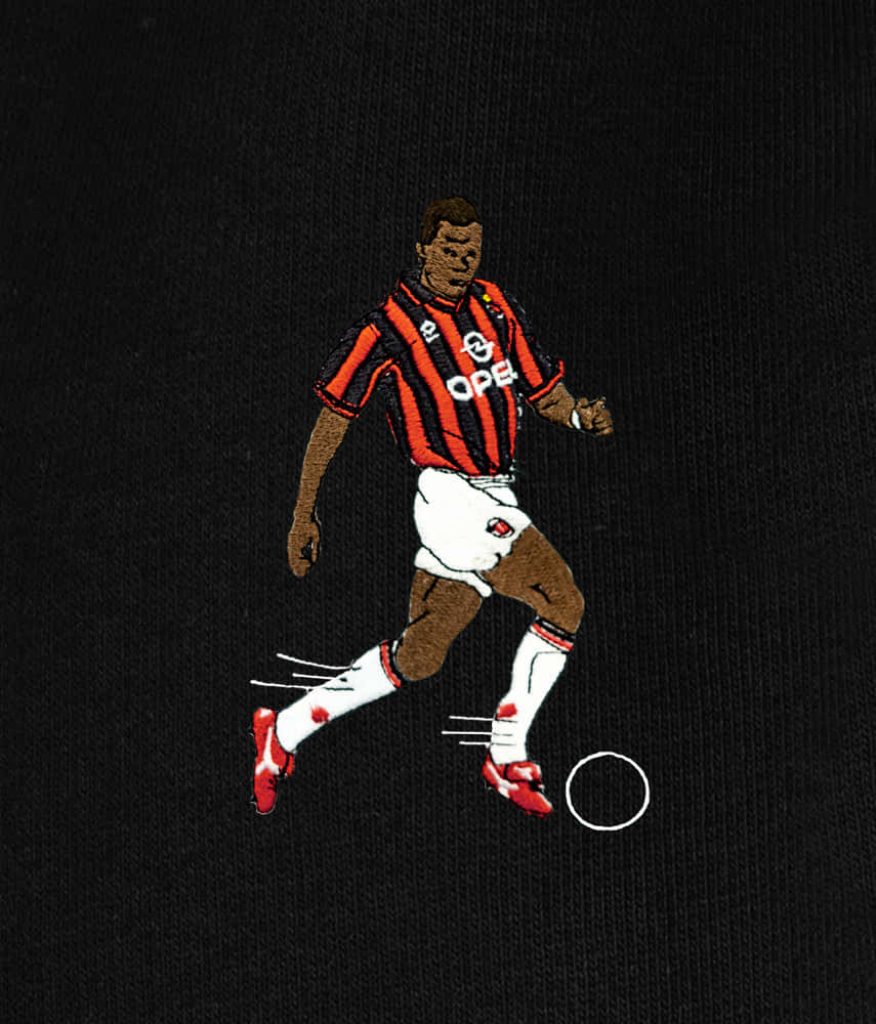 Embroidered patch of AC Milan legend George Weah in red black kit mid-dribble on black background Wallpaper