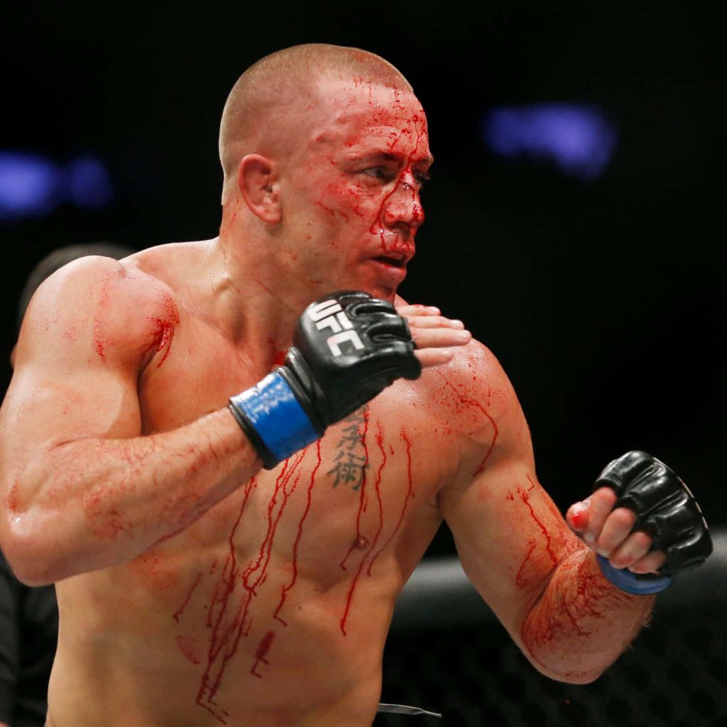 Georges St-Pierre intense UFC fight action high-definition MMA wallpaper with blood and arena lighting