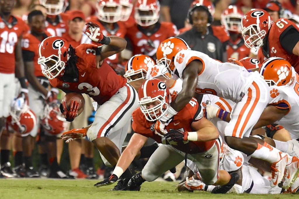 Georgia Bulldogs football player tackling Clemson Tigers under bright stadium lights wallpaper