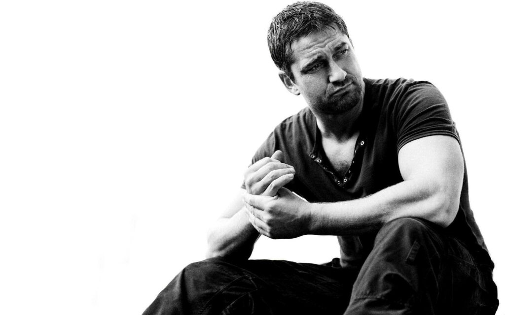 Gerard Butler confident pose black and white wallpaper rugged charm strong presence background
