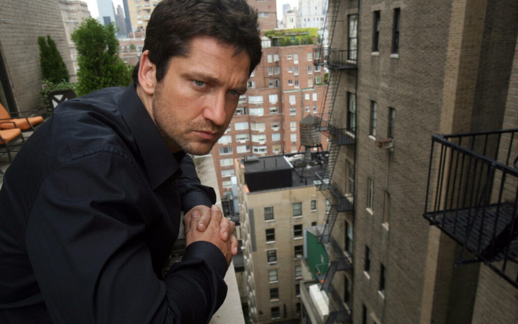 Gerard Butler on city balcony serious expression overlooking tall buildings Olympus Has Fallen wallpaper