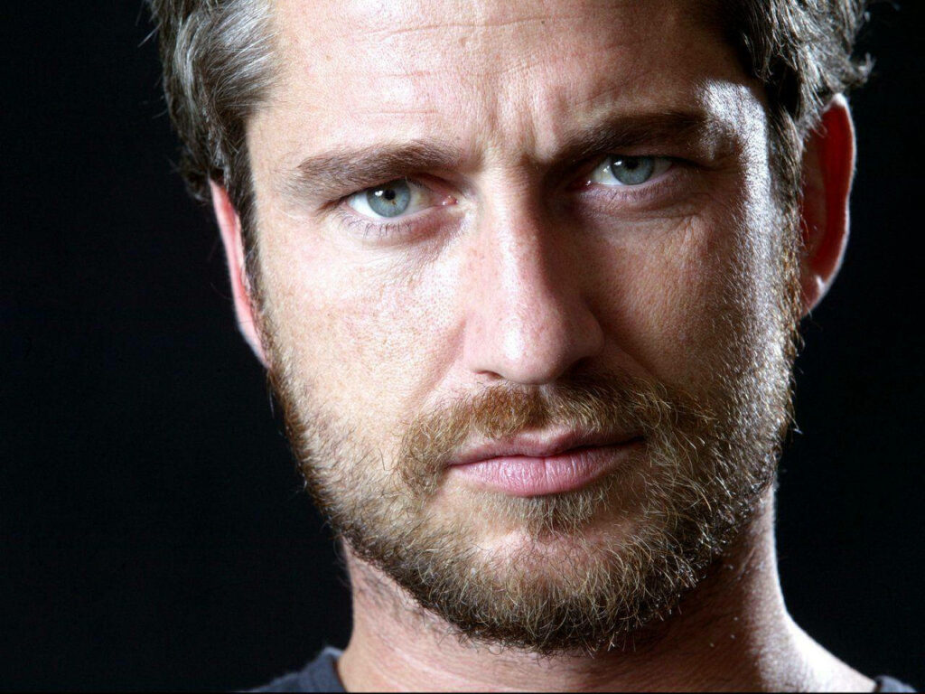 Close-up portrait of Gerard Butler with intense gaze and rugged features on dark background Wallpaper