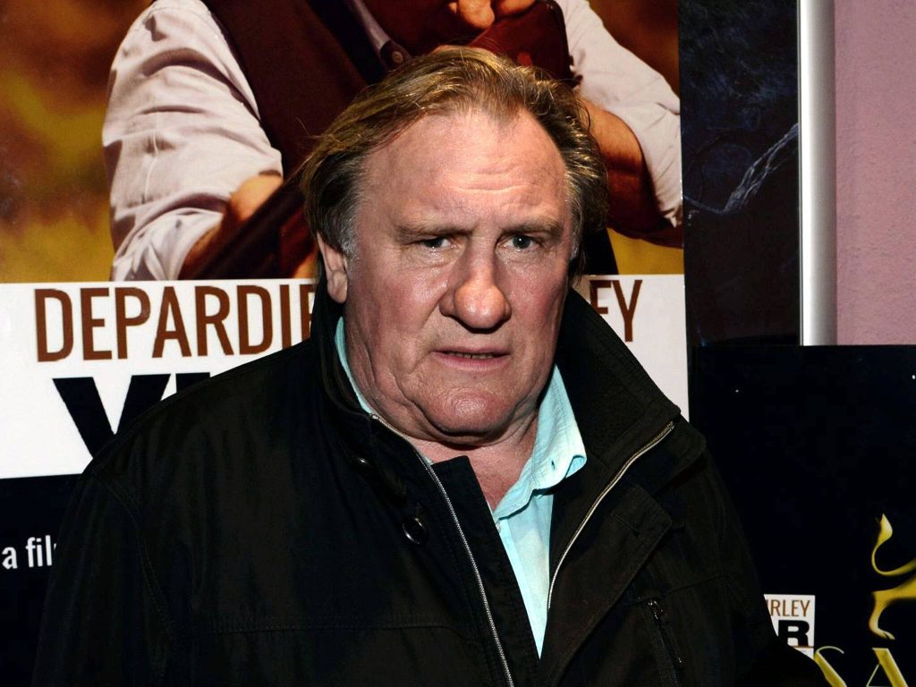 Gérard Depardieu candid portrait dark jacket light shirt movie poster background French actor Wallpaper