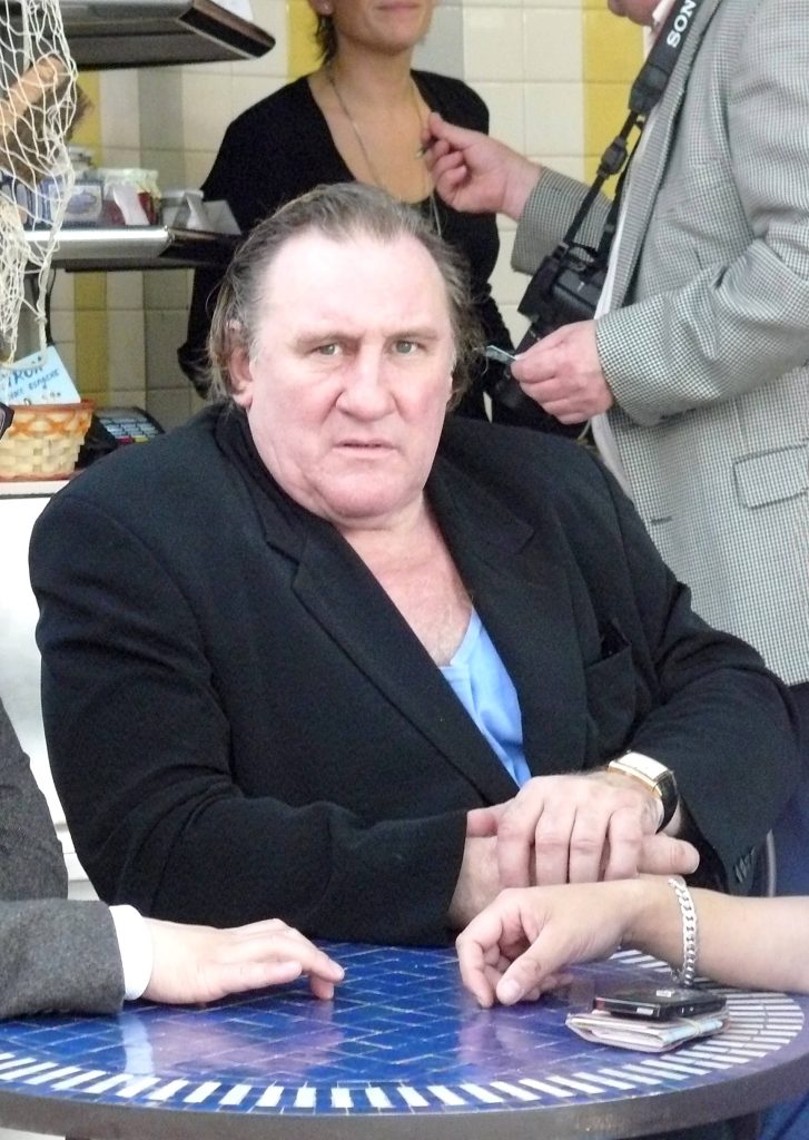 Gérard Depardieu sitting at blue mosaic table wearing black blazer candid celebrity photo wallpaper