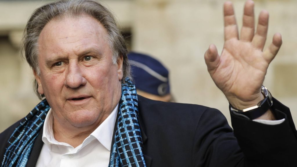 Gérard Depardieu waving in dark blazer white shirt patterned scarf high quality wallpaper