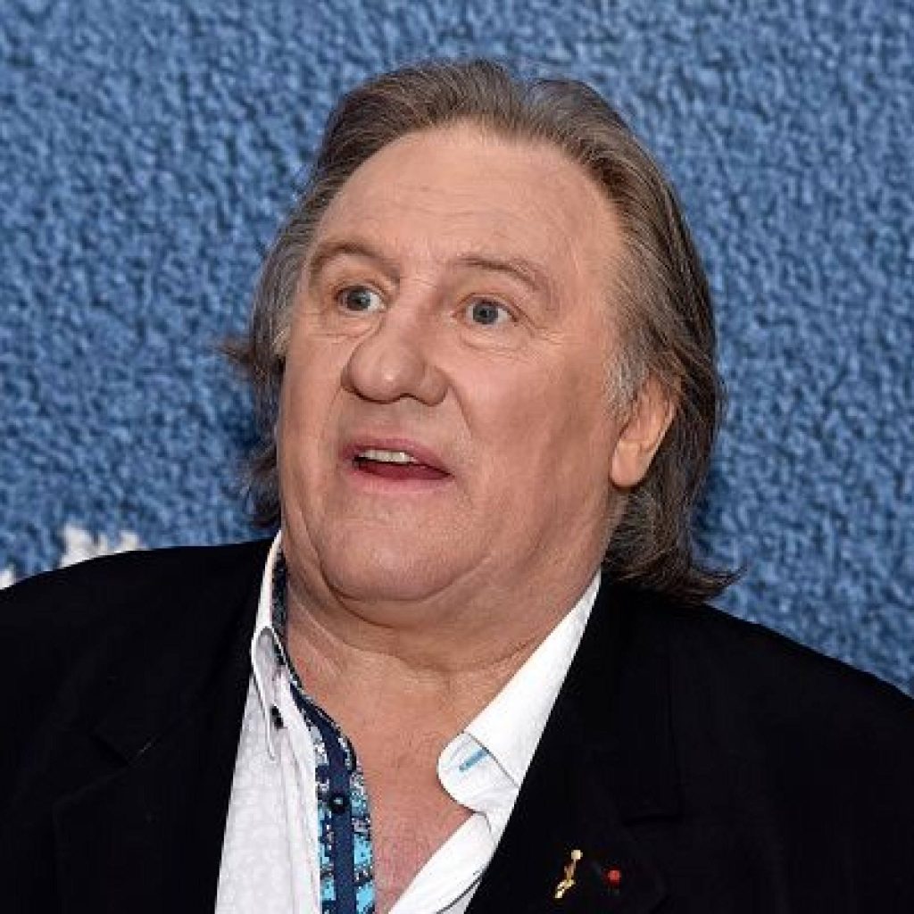 Portrait of French actor Gérard Depardieu in black blazer with textured blue background wallpaper