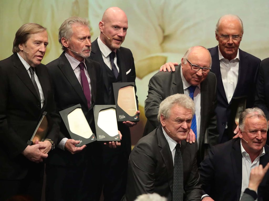 German Football Hall of Fame legends Netzer Breitner Sammer Beckenbauer hold plaques in ceremony Wallpaper