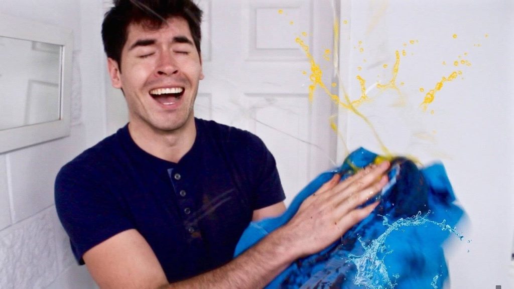 YouTube star Germán Garmendia laughing with blue cloth yellow liquid splashes white background Wallpaper