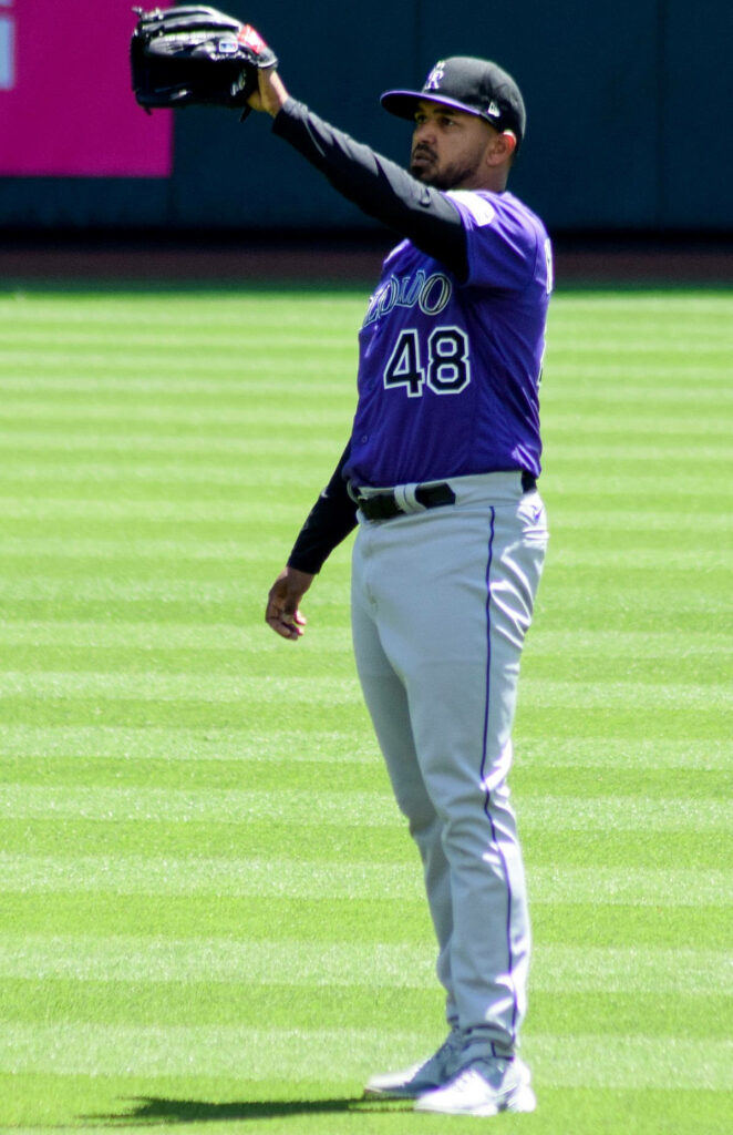 German Marquez Colorado Rockies catching baseball on green field in purple jersey and gray pants Wallpaper