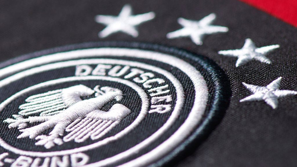 Germany National Football Team embroidered eagle patch with three stars on black fabric background Wallpaper