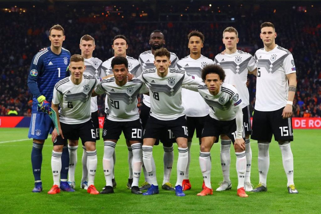 Germany National Football Team in white black kits posing on pitch under bright stadium lights wallpaper