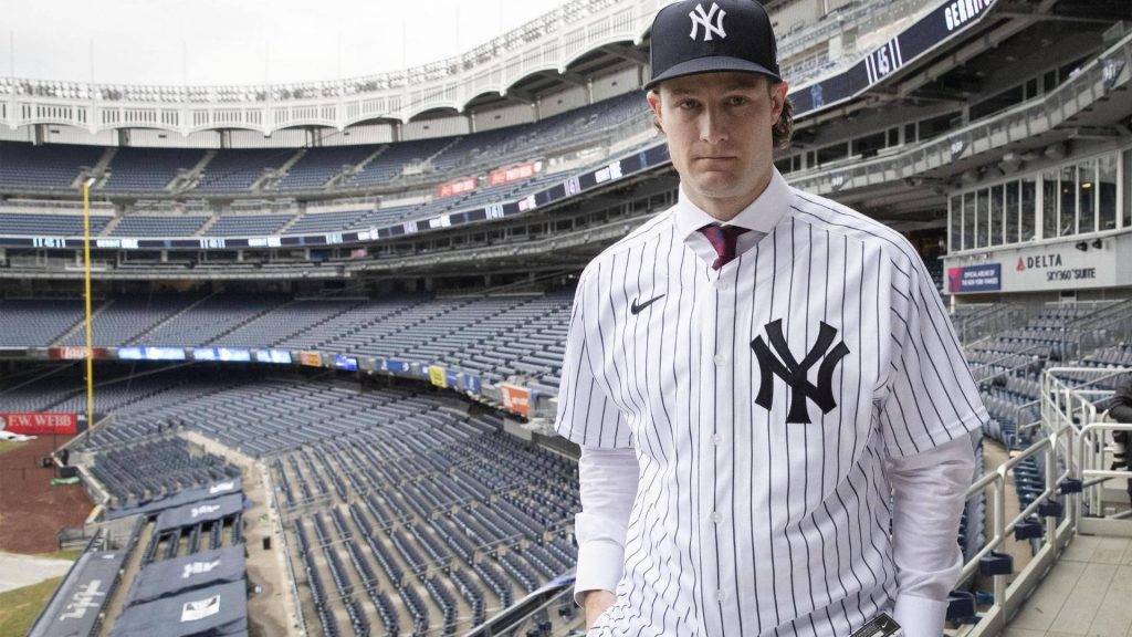 Yankees ace Gerrit Cole pitching in pinstripe uniform with blurred empty Yankee Stadium background Wallpaper