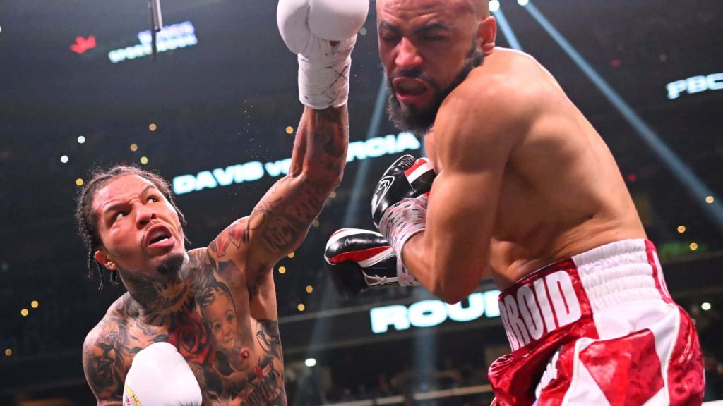 Gervonta Davis striking Rolando Romero in intense boxing match with dramatic arena lighting Wallpaper