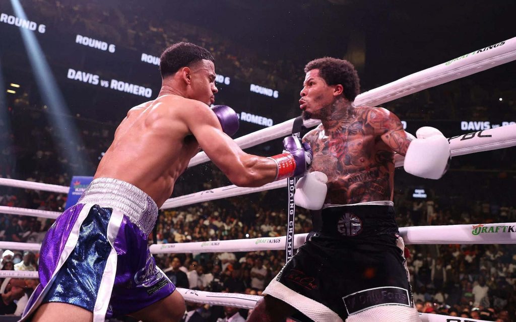 Gervonta Davis and Rolando Romero intense Round 6 boxing exchange under bright stadium lights Wallpaper