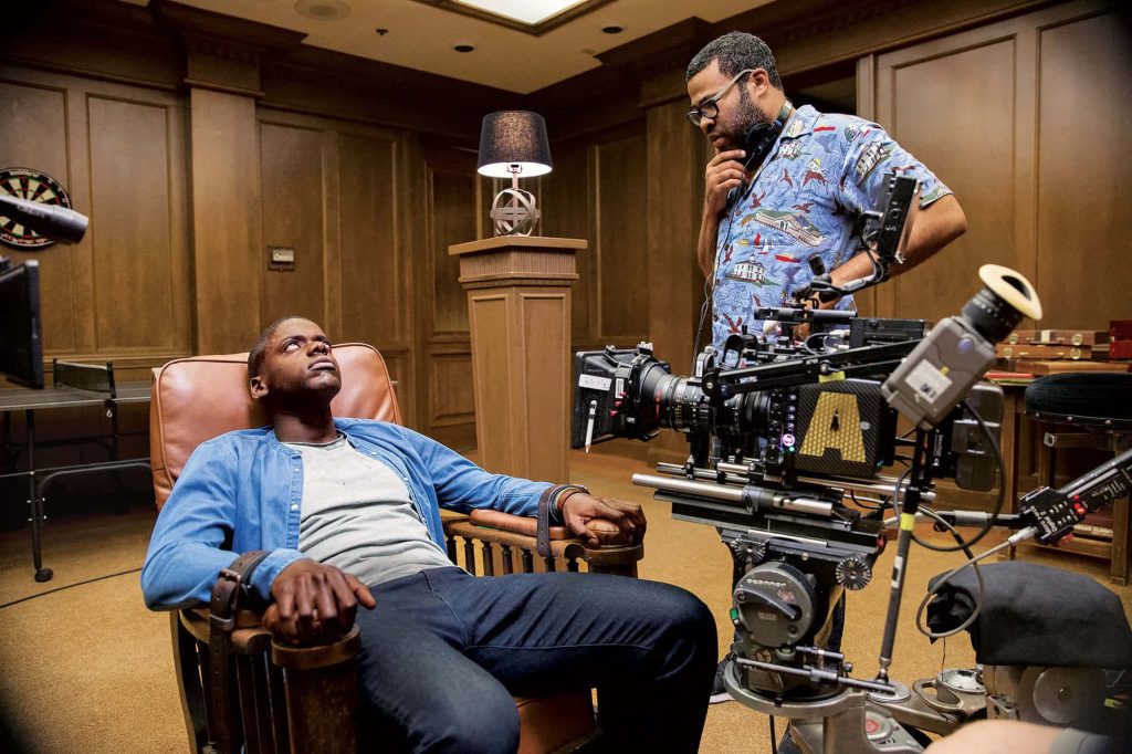 Jordan Peele directing Daniel Kaluuya in Get Out Sunken Place scene on wood-paneled set wallpaper