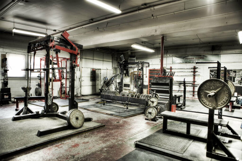 Industrial Gym with Barbells, Squat Racks, and Leg Press Machine Wallpaper - QHD Fitness Background