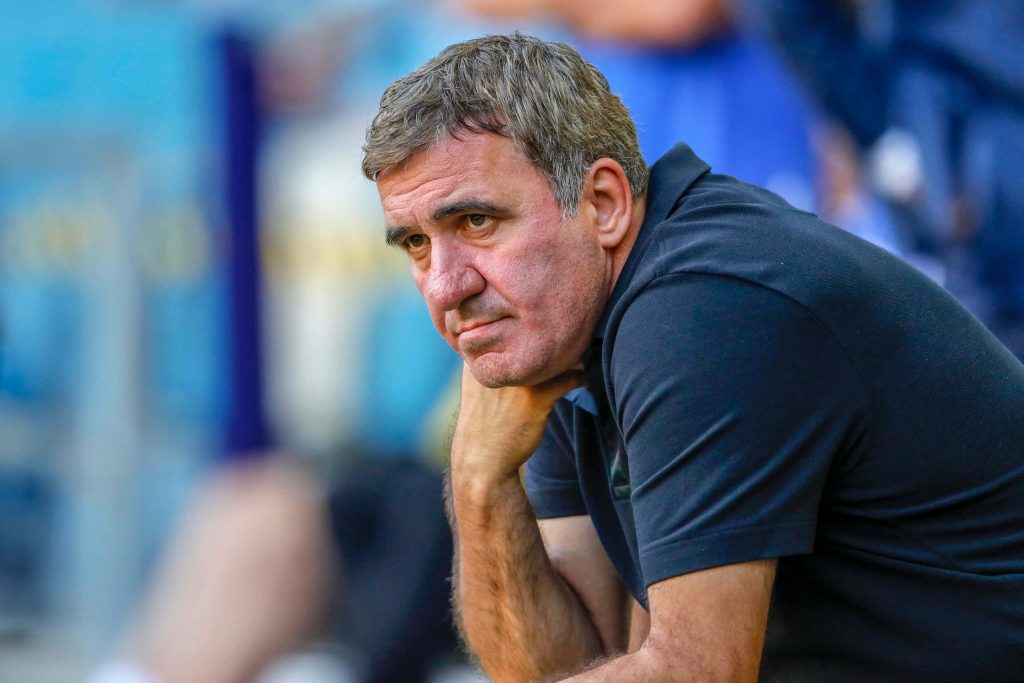 Gheorghe Hagi deep in thought coaching Romanian football in blurred stadium background Wallpaper